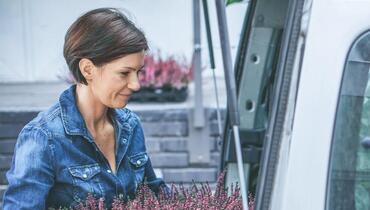 Frau lädt Blumen in kleinen Transporter 